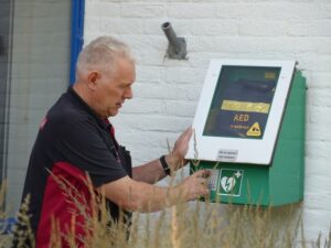 Gauke Hayma controleert een AED die buiten aan de muur hangt.