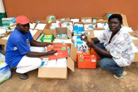Twee mensen in Gambia zitten voor een lading EHBO-materialen die is gedoneerd door deBesteEHBOdoos.
